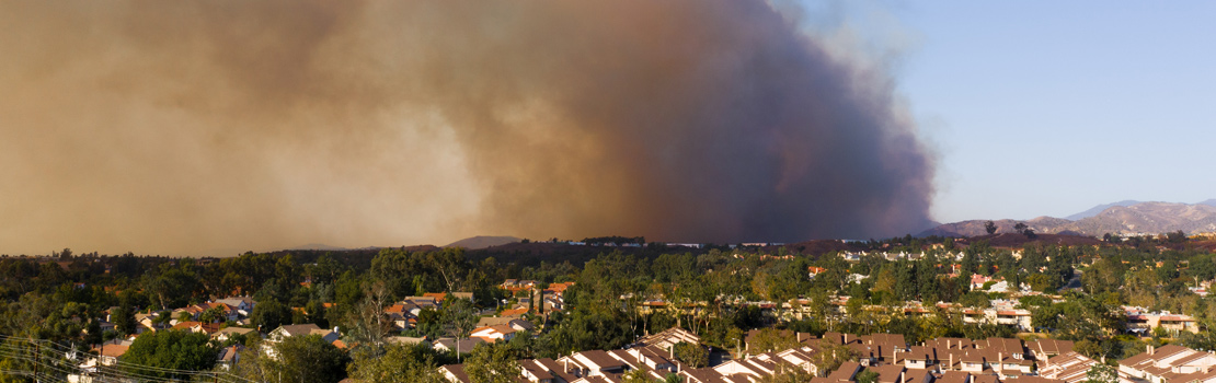 Fire management in Australia is a key issue. A neighbourhood is in the front of the picture while a large cloud of 